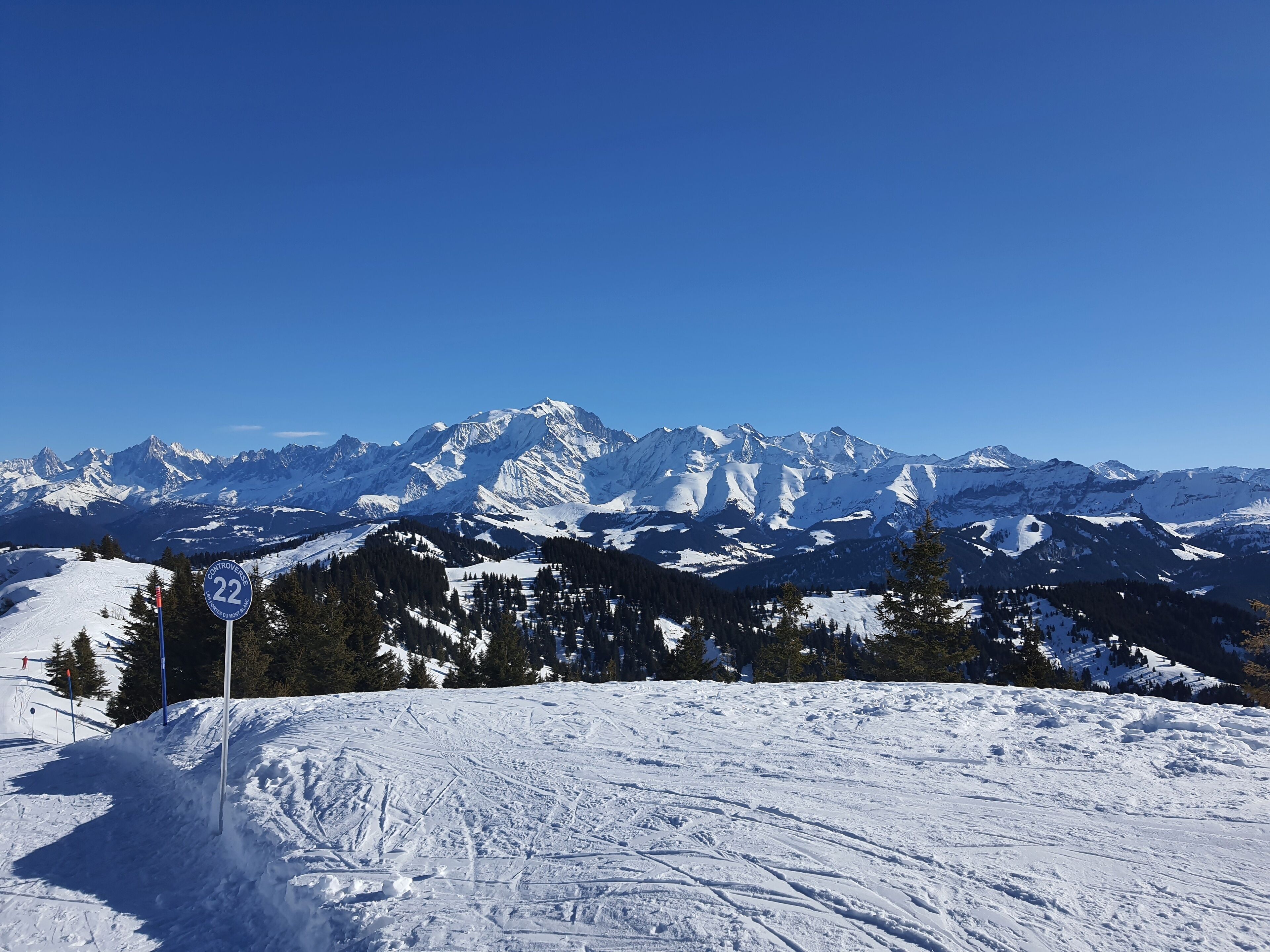 Eine verschneite Berglandschaft mit einem Schild, das eine Skipiste anzeigt.