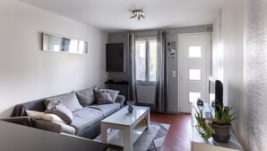 Ein modernes Wohnzimmer mit einem grauen Sofa, einem weißen Couchtisch und einem Fernseher auf einem Lowboard.