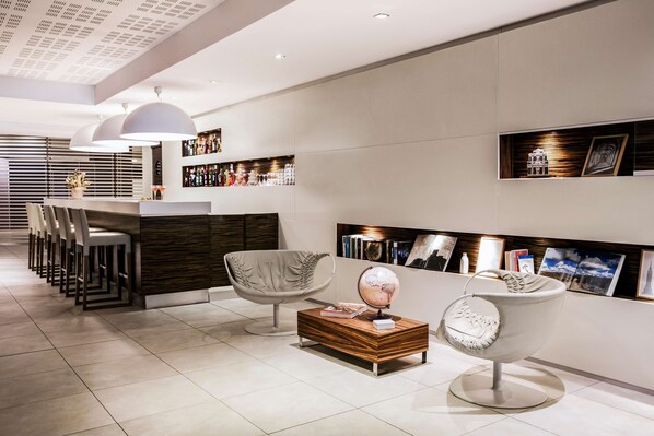 Een modern interieur met een bar, zitplaatsen en een presentatie van boeken en kunstwerken.