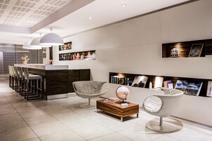 Un interno moderno con un’area bar, posti a sedere e una collezione di libri e opere d'arte.