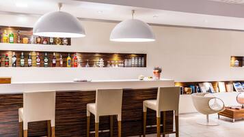 A modern bar area with a wooden accent wall, multiple liquor bottles, and pendant lighting.
