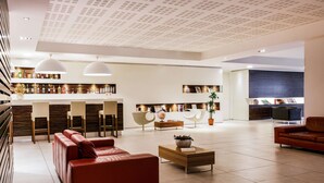 Een ruime, moderne woonkamer met een rode leren bank, een houten salontafel en een bar voorzien van flessen en boeken.