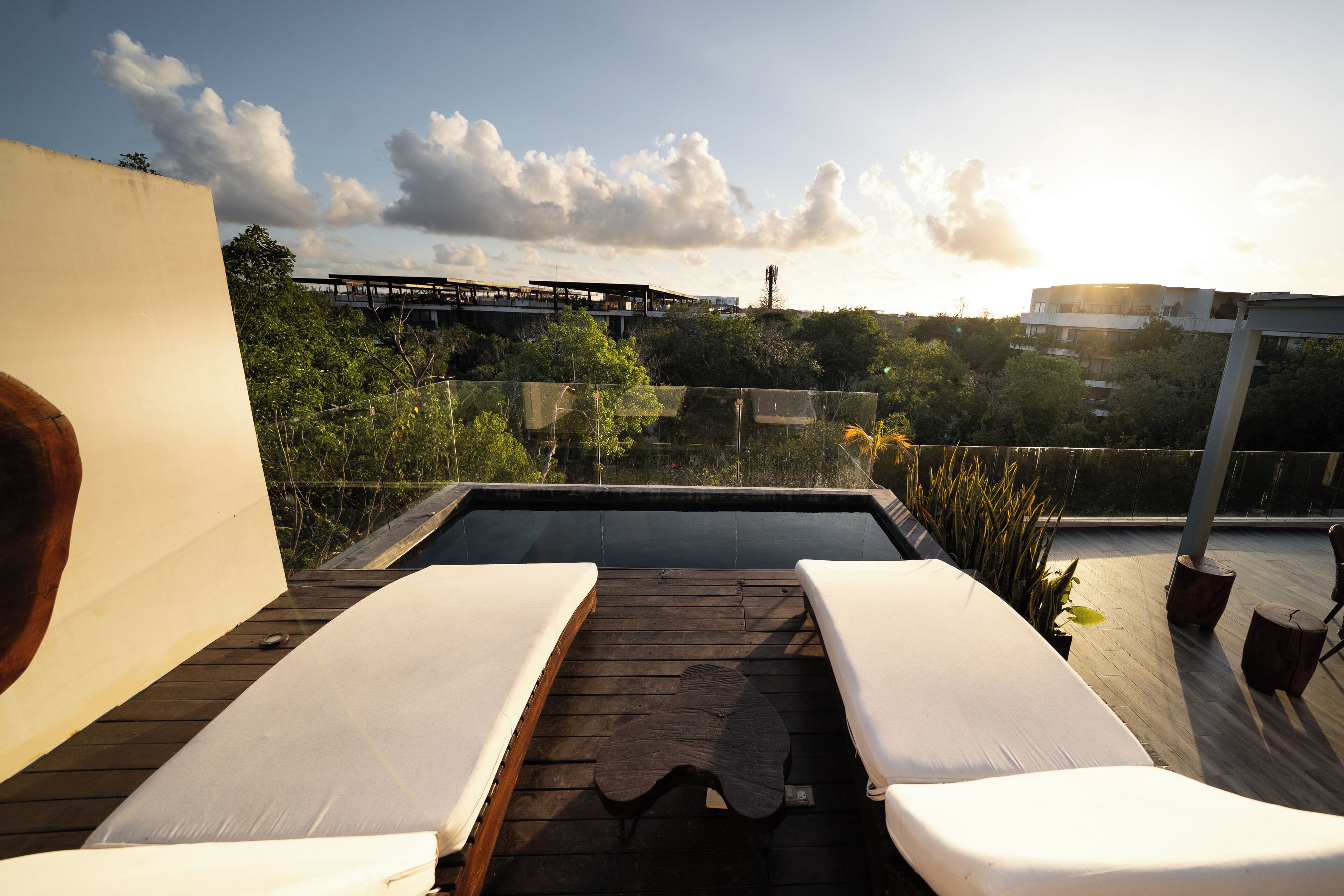 A rooftop terrace with two sun loungers, a wooden deck, and a view of a bridge and buildings in the background.