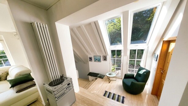 A spacious loft with high ceilings, large windows, a fireplace, and a cozy seating area. - Holiday home mountain idyll (Sasbachwalden)