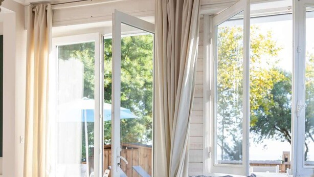 A modern living room with a grey sofa, a small round table, and a wicker chair. - Villa Claire à Andernos - sea view with heated poo (Andernos-les-Bains)