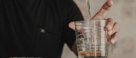 A person pouring a dark liquid into a clear glass.