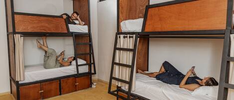 A dormitory room with bunk beds, wooden frames, and a simple layout.