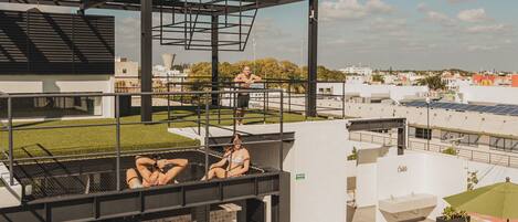 A rooftop pool area with clear water, a covered seating area, and a view of the surrounding buildings.
