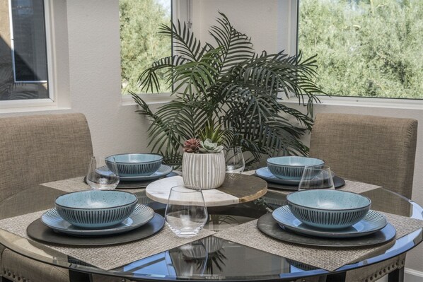 A round dining table with blue and white plates, a central vase with succulents, and a view of greenery through a window. - Luxury Private Townhome @ TPC | GOLF Garage & Pool (Scottsdale)