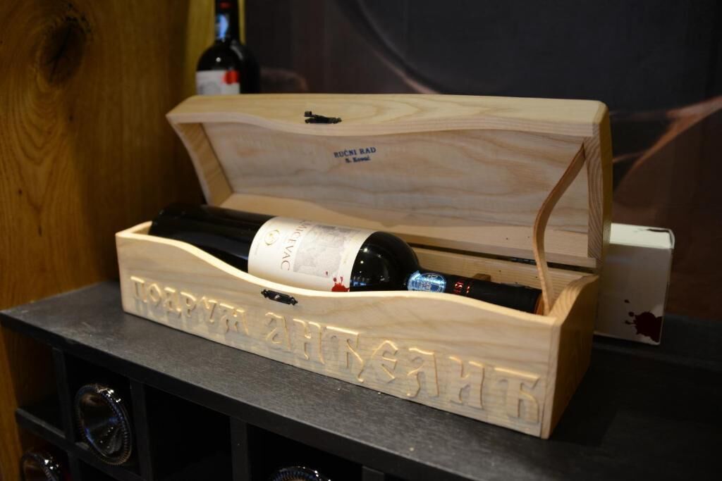 A wooden wine chest with a bottle of wine inside.