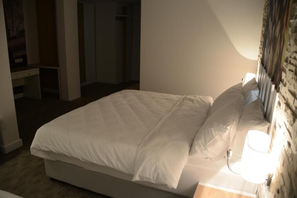 Una cama bien hecha con ropa blanca en una habitación de hotel.