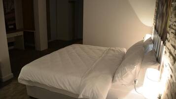 Una cama bien hecha con ropa blanca en una habitación de hotel.