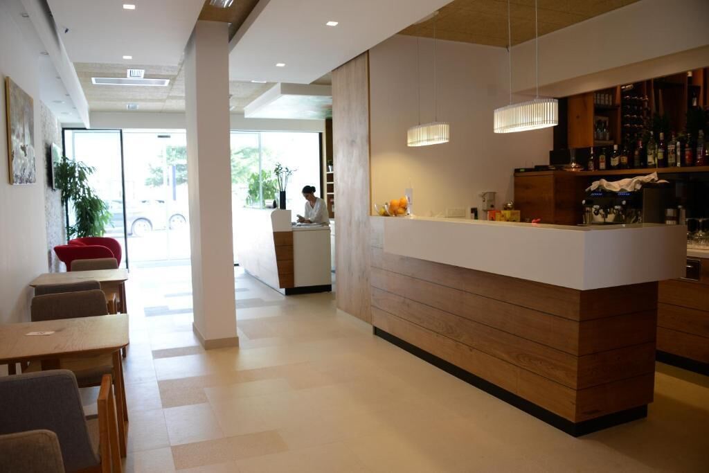 A modern hotel lobby with a reception desk, seating area, and a bar.