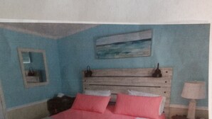 Una camera da letto con un letto, un comodino, una lampada e un quadro appeso al muro.
