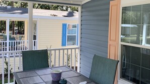 Un patio coperto con tavolo, sedie e ventilatore a soffitto.