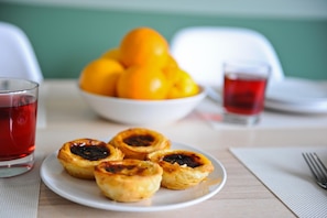 Un plato de pasteles portugueses de crema pastelera y un bol de naranjas sobre una mesa.