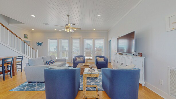 A living room with a sofa, two armchairs, a coffee table, a TV, and a ceiling fan. - Biscayne Seaglass: 4 BR, 3 BA House in Port Bolivar, Sleeps 12 (Bolivar Peninsula)
