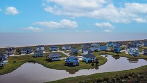 A coastal residential area with houses, a beach, and a body of water. - Biscayne Seaglass: 4 BR, 3 BA House in Port Bolivar, Sleeps 12 (Bolivar Peninsula)