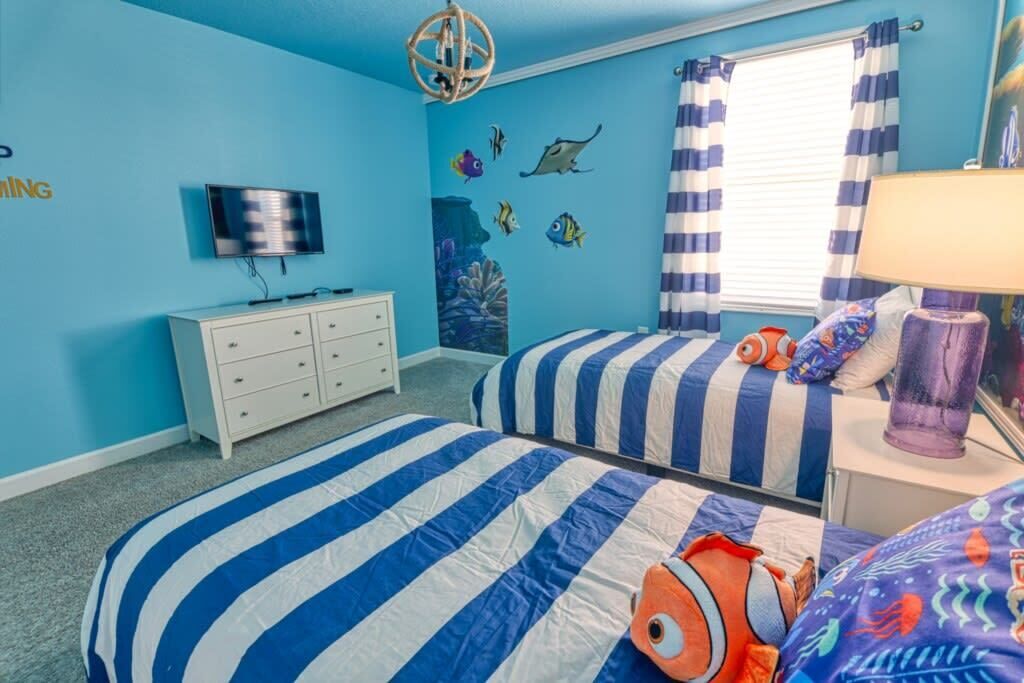 A bedroom with two beds, a dresser, a TV, and a window with curtains.
