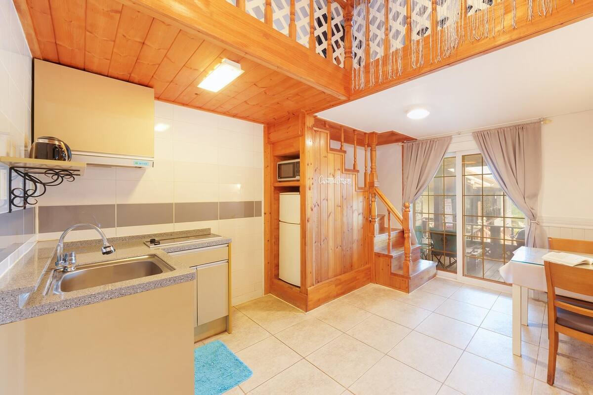 A modern kitchen with a built-in oven, a sink, and a dining area with a table and chairs.