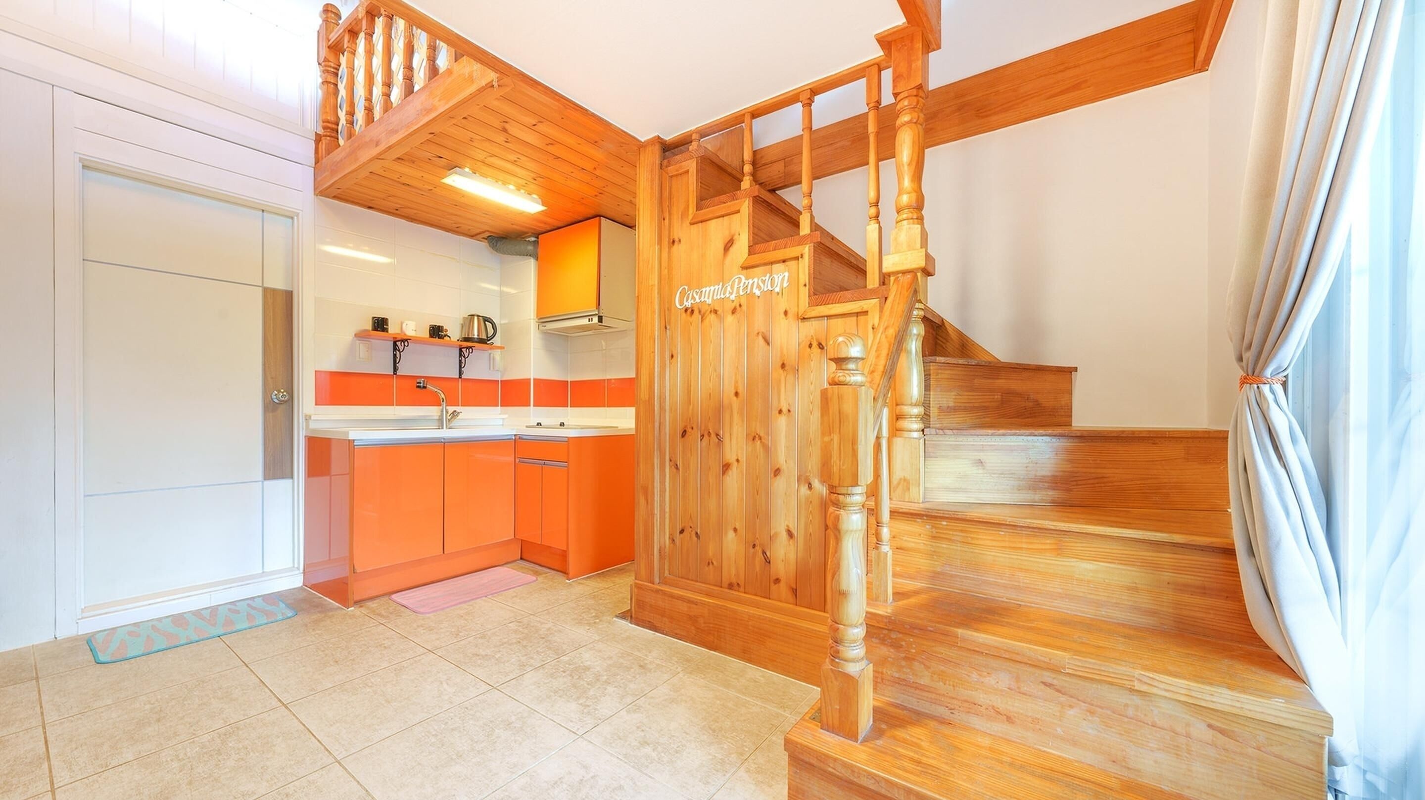 Una cocina con armarios naranjas, una escalera de madera y un letrero que dice 'Casamasso Ferraz'.