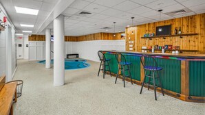 A bar area with a pool, wooden paneling, and bar stools. - Pinnacle A19 (Killington)