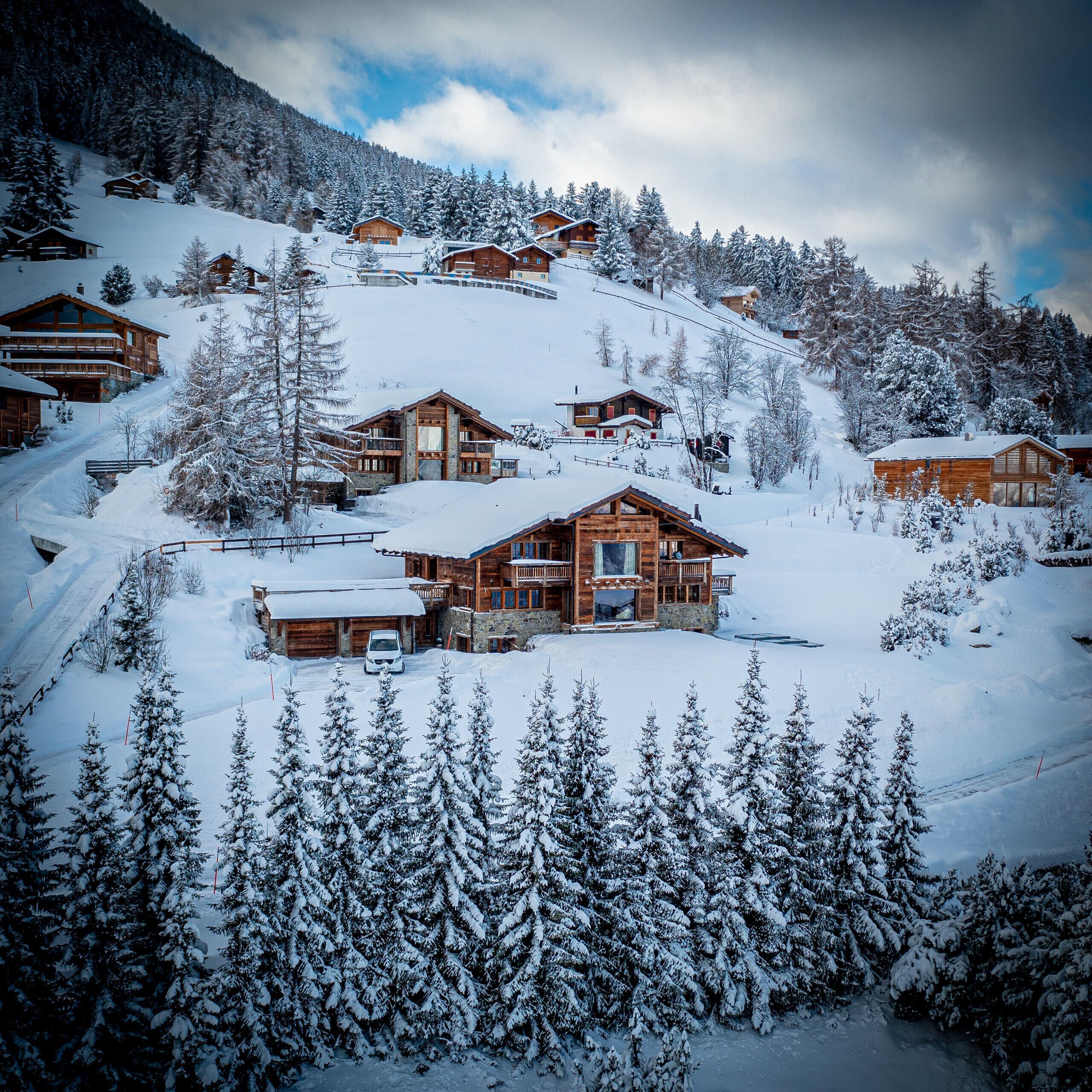 A snow-covered mountain resort with wooden cabins and ski slopes.