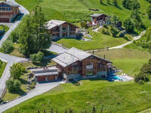 A large wooden lodge with multiple rooms, a swimming pool, and a scenic hillside view. - Luxury Alps Chalet YOLO (Haute-Nendaz)