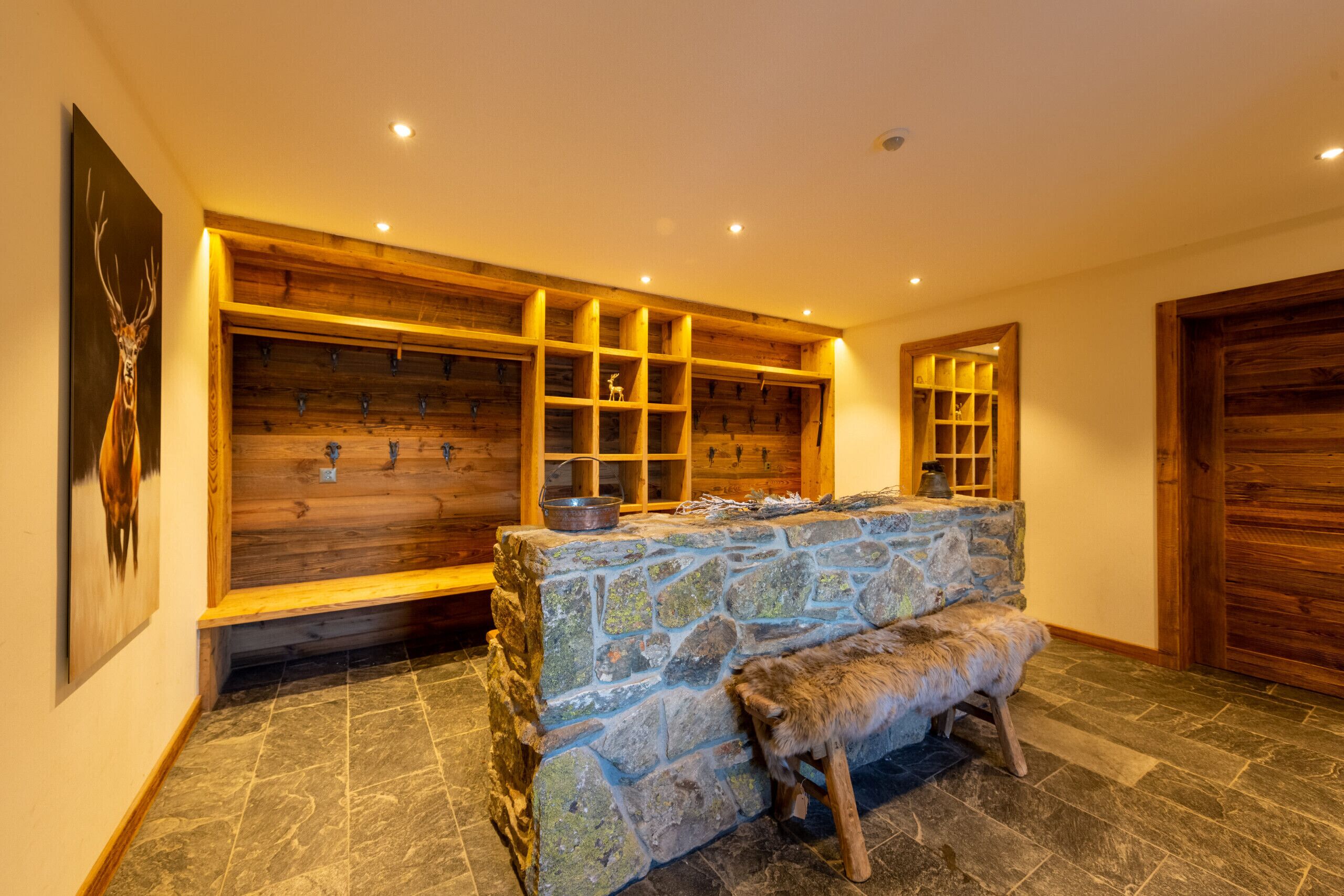 Une cheminée en pierre avec un banc, des étagères en bois et un mur en bois rustique.