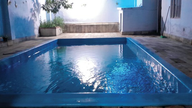 A rectangular swimming pool with a tiled deck surrounding it. - Pousada CNU (Rio de Janeiro)