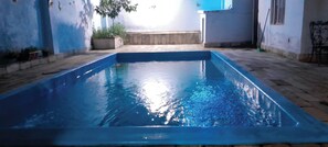 A rectangular swimming pool with a tiled deck surrounding it.