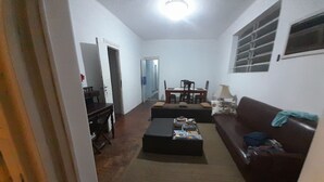 A living room with a sofa, a coffee table, a dining table with chairs, and a door leading to another room. - Pousada CNU (Rio de Janeiro)