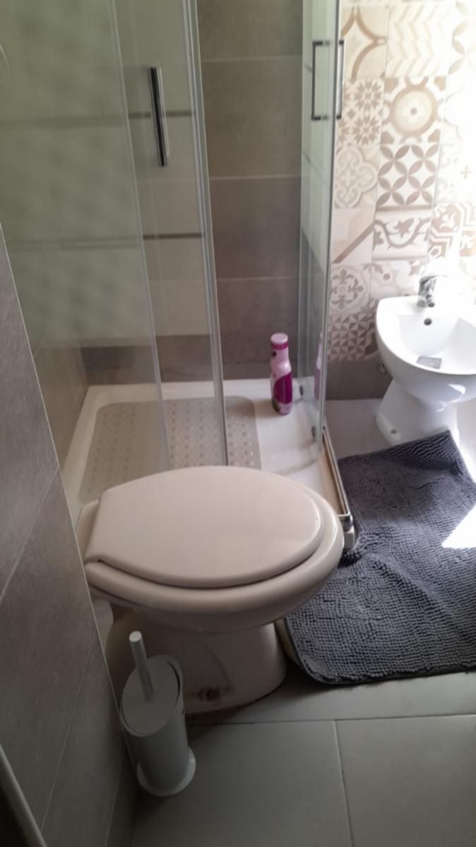 Un baño con inodoro, cabina de ducha, lavabo y pared con diseño.