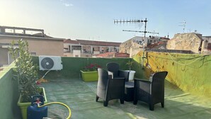 A rooftop terrace with a table and chairs, a potted plant, a water heater, and an air conditioning unit. - Civic 10 II Spacious studio apartment with terrace above at Sassari Center (Sassari)