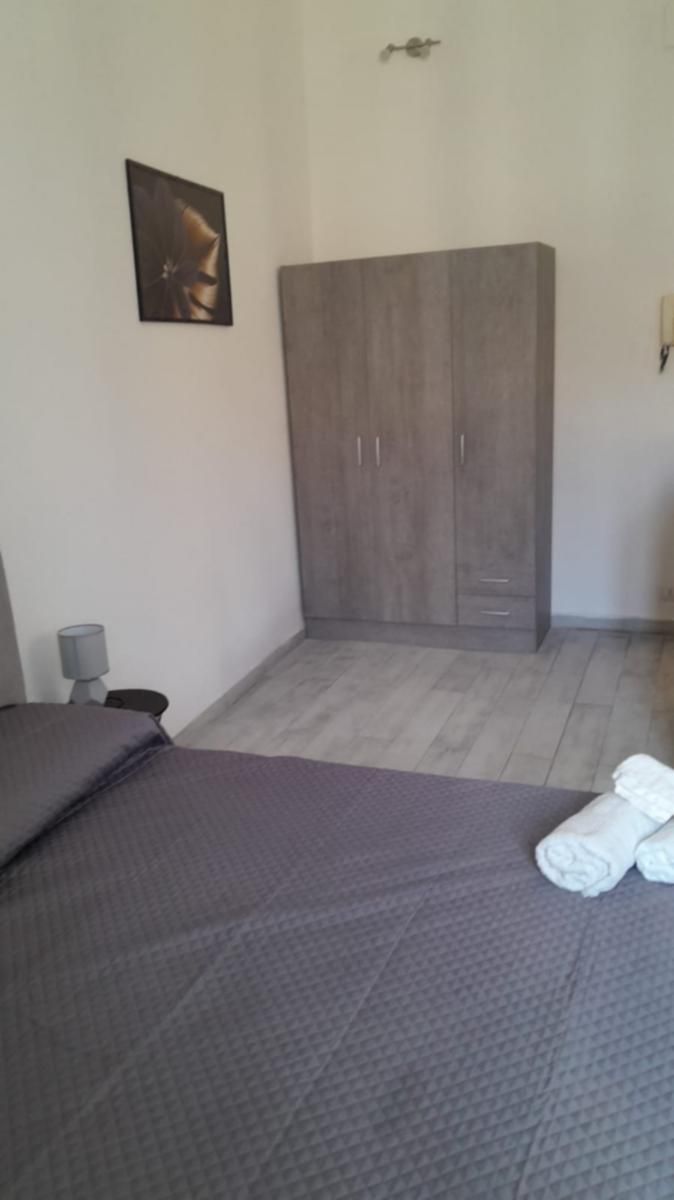Ein Schlafzimmer mit einem Bett, einem Kleiderschrank, einer Lampe und einem Gemälde an der Wand.
