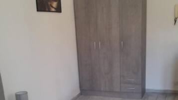 Ein Schlafzimmer mit einem Bett, einem Kleiderschrank, einer Lampe und einem Gemälde an der Wand.