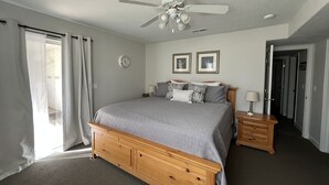 Een slaapkamer met een bed, een plafondventilator, een klok en ingelijste foto's aan de muur.