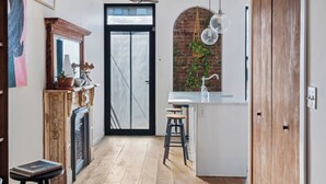 Une cuisine moderne avec une porte noire, un plancher en bois et un mur en briques.