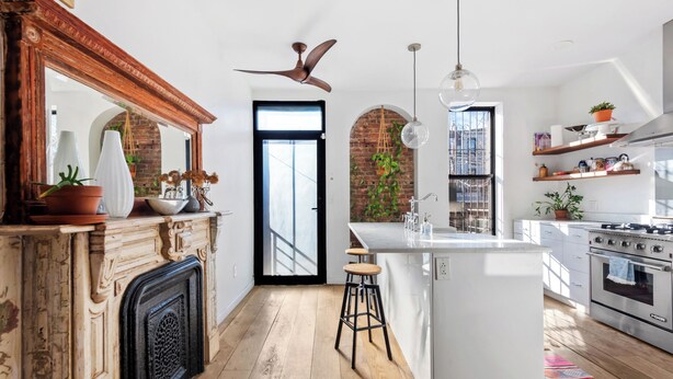 Une cuisine moderne dotée d’un îlot central, d’un plancher en bois et d’un mur en briques.