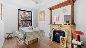 Une pièce comprenant une table à manger dressée pour quatre personnes, une cheminée et un grand miroir au-dessus.