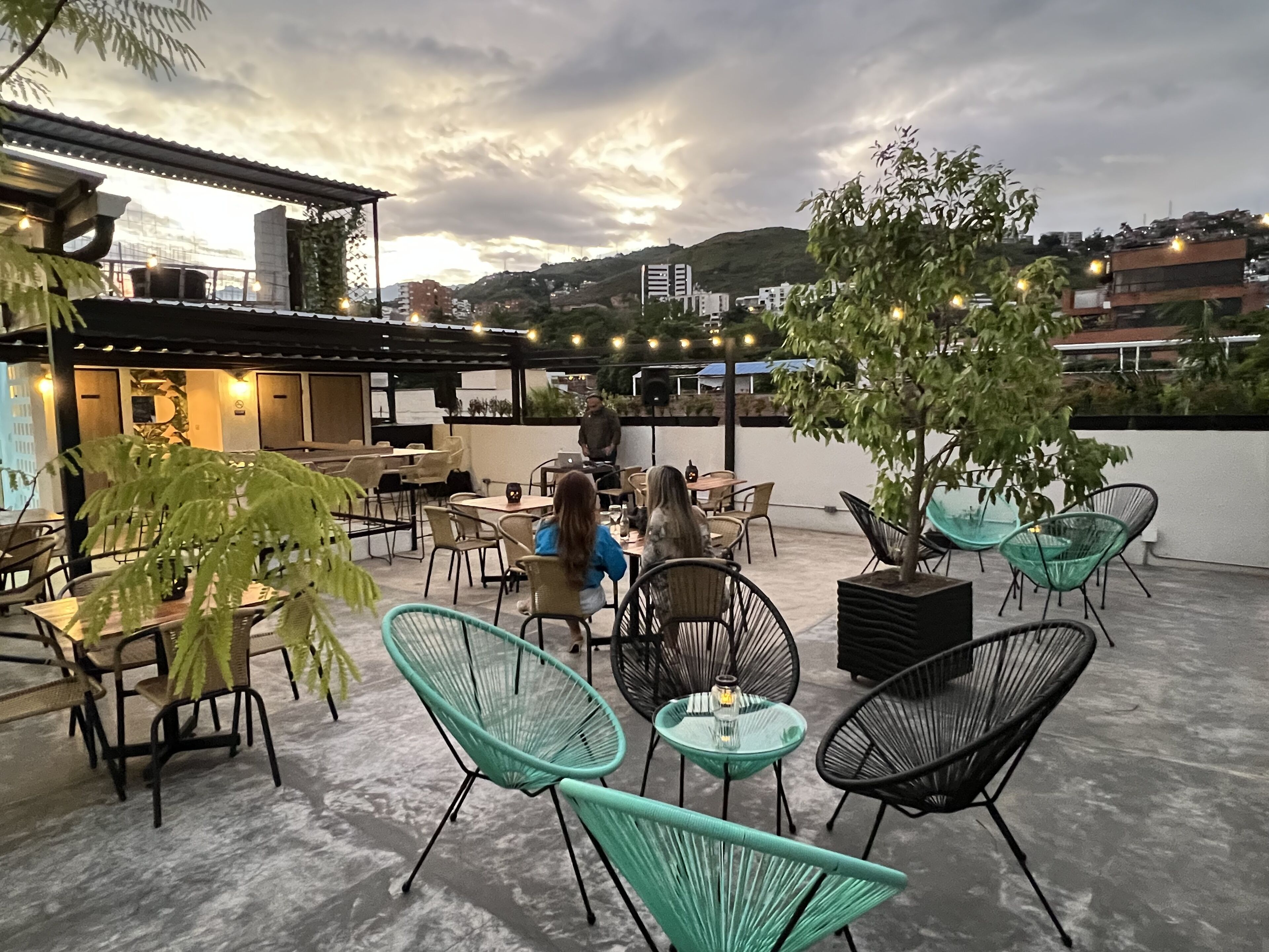 Eine Außenpatio mit Tischen, Stühlen, einer kleinen Bar und Blick auf die Skyline.