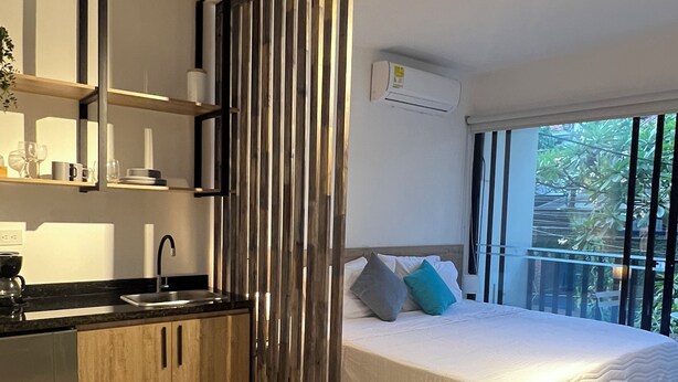 Een moderne slaapkamer met een groot bed, een ingebouwd bureau en een keukenhoek.