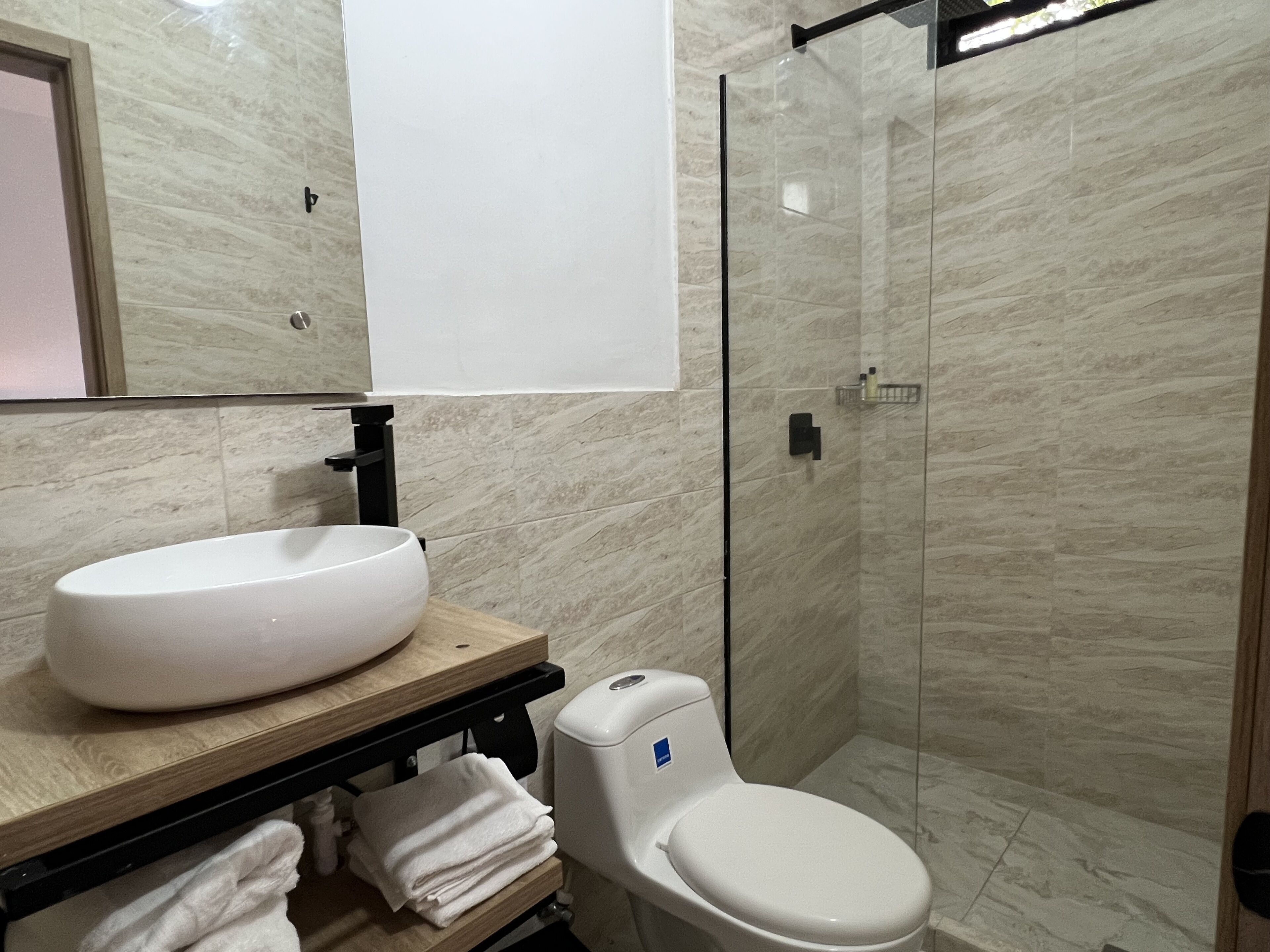 Een badkamer met een wit wastafel, toilet en een douchecabine van glas.