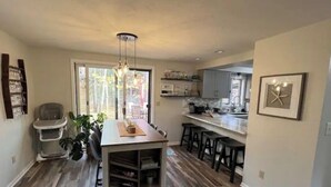 A modern kitchen with a central island, bar stools, and a high ceiling. - Coastal theme/wooded & large deck/fenced-in yard (Holland)