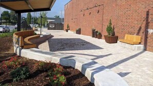 Une cour dotée d’un espace de repos abrité, de murs en briques et de plantes en pot.