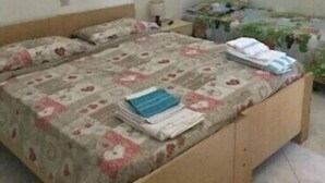 Un dormitorio con dos camas de madera, una mesita de noche pequeña, una lámpara y un cuadro enmarcado en la pared.