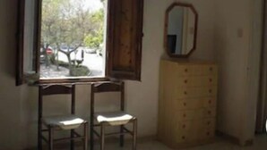 Una habitación con un ventanal grande, dos sillas, un aparador y un espejo.