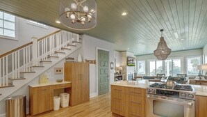 A modern kitchen with a Jenn-Air stove, wooden cabinets, and a staircase with white railings. - Grand Pavilion 15 - Oceanfront Home! GP Pool Pass! (Isle of Palms)