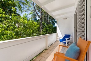 A balcony with a white railing, a blue chair, and a wooden chair. - Kareela Court 4 Kareela Avenue 14 (Noosa Heads)
