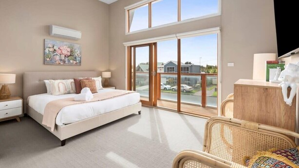 Une chambre à coucher avec un grand lit, une fenêtre, une chaise et une commode.